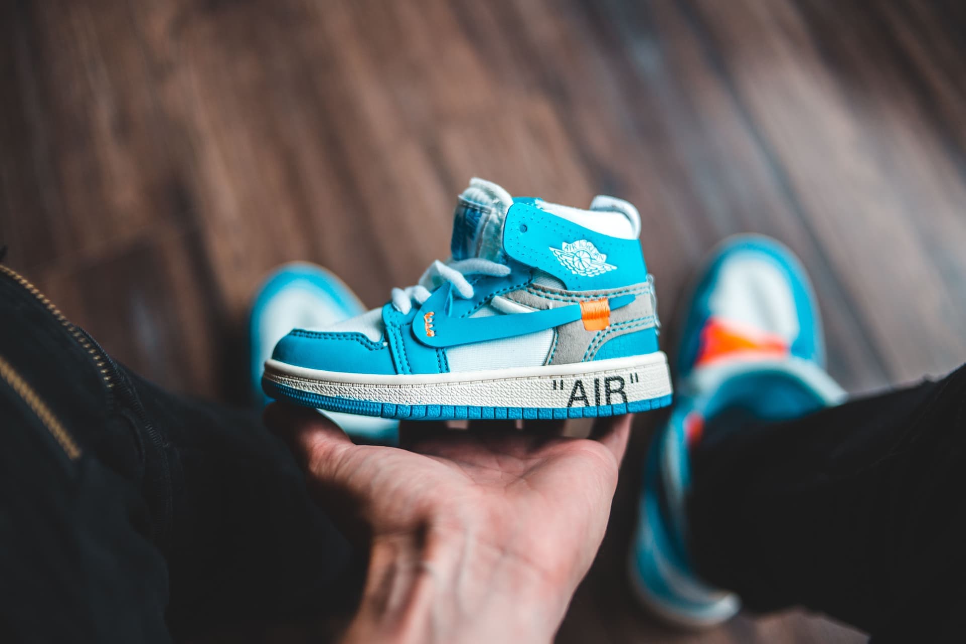 A person holding a small child's blue sneaker in a bright room