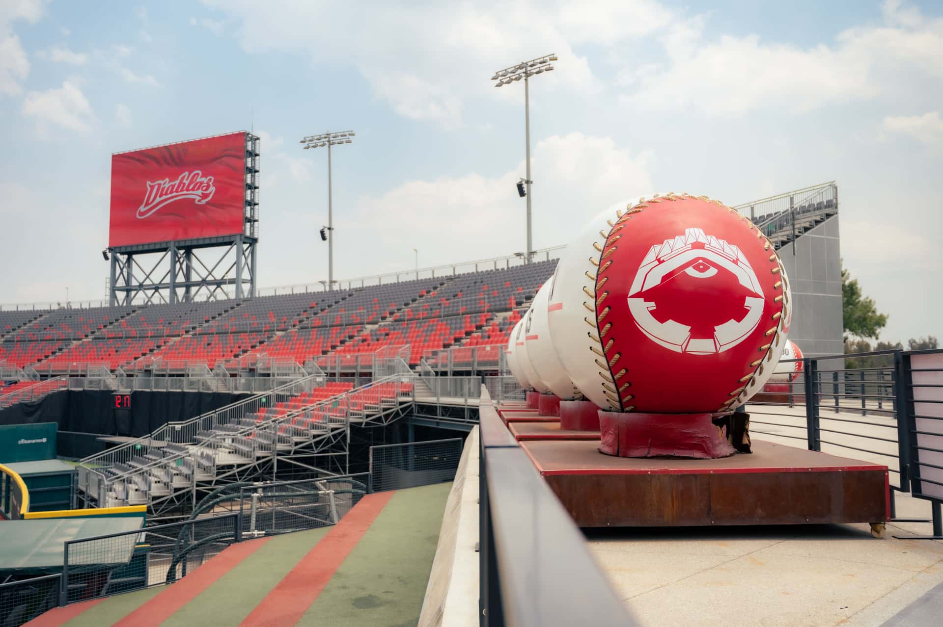 An empty ballpark with oversized baseball decorations under a clear sky