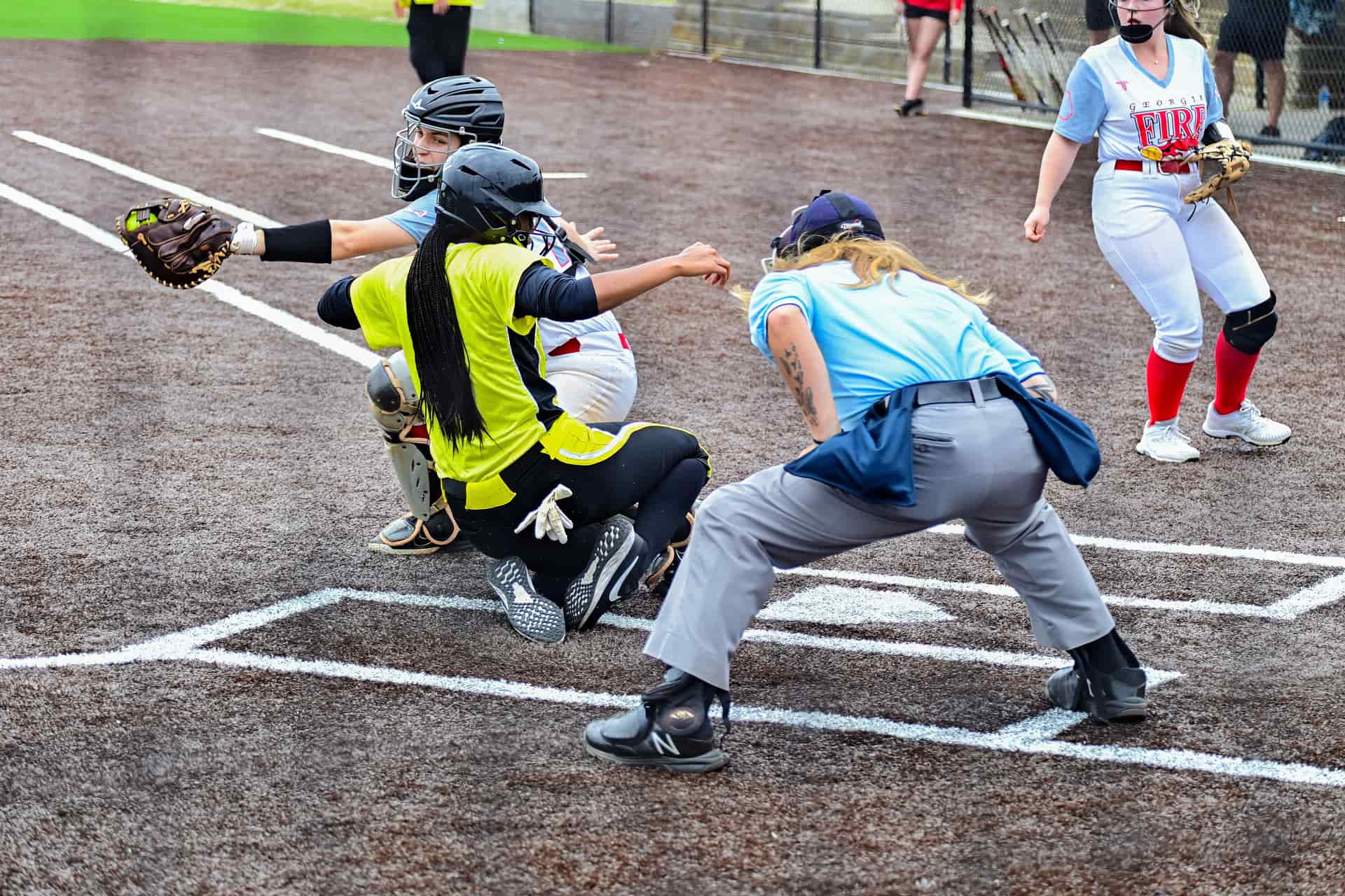 A softball player sliding into home plate during a game